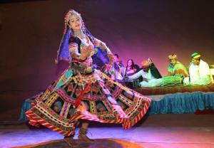 een vrouw in een kleurrijke jurk danst voor een groep mensen bij Golden haven hotel & resort in Jaisalmer