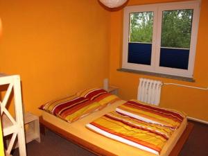 a bedroom with a bed with orange walls and two windows at Ferienwohnung Rügen in Samtens in Samtens