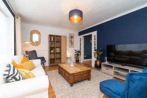 a living room with a white couch and a tv at WiFi | Parking | Near Major Attractions in Bath