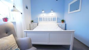 ein weißes Bett in einem blauen Zimmer mit einem Stuhl in der Unterkunft MCEW Studnia in Płock