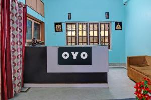 a sign on a desk in a room with a couch at OYO Archie Oasis in Bhubaneshwar