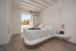 a white bedroom with a large white bed and a window at Akkadian LGBT Only Boutique Hotel in Mikonos