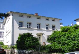 a white building with trees in front of it at Villa Monique in Alt-Sassnitz in Sassnitz