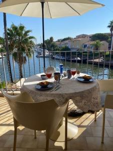 コゴランにあるPCOGPET - Golfe de St-Tropez - Appartement au bord de l'eau avec piscineのテーブル(お皿、グラスワイン付)