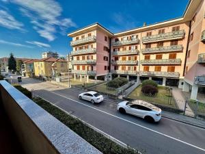 twee auto's rijden door een straat voor een gebouw bij [near Orio] BGY Malpensata HOUSE in Bergamo