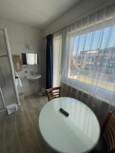 ジュネーヴにあるPrimadom Aparthotelの白いテーブル、洗面台、窓が備わる客室です。