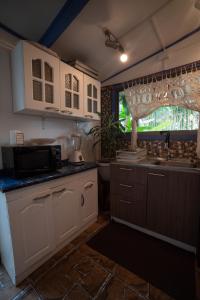 eine Küche mit weißen Schränken, einem Waschbecken und einem Fenster in der Unterkunft Hare Isolate in Hanga Roa