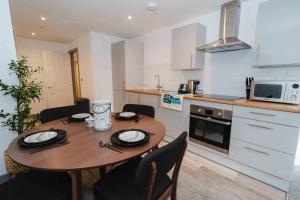 a small kitchen with a wooden table and chairs at George House Modern Apartments by VICHY in Hull