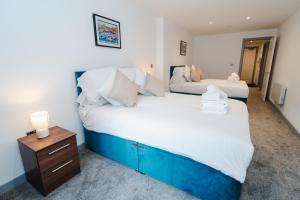 two beds in a bedroom with a nightstand and a bed sidx sidx sidx sidx at George House Modern Apartments by VICHY in Hull