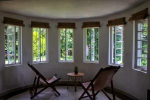 um grupo de janelas num quarto com cadeiras em Silvawood Banglow em Rangala