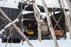 a log cabin in the snow with a yellow chair at Kussharoko Sauna Club in Teshikaga