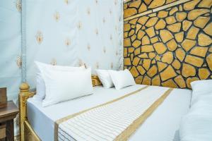 a bed with white pillows and a stone wall at Sandcastle Resort in Jaisalmer