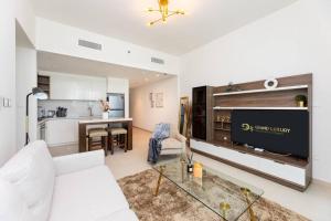 a living room with a white couch and a tv at Sunny Downtown Retreat- Direct access to Dubai Mall in Dubai