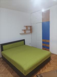 a bedroom with a green bed and a cabinet at Стан in Prilep