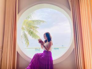 Una mujer con un vestido púrpura mirando su móvil en sunset beach house 3, en Phu Quoc
