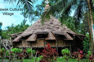 uma cabana com um telhado de palha e uma palmeira em Riverbank Suite @ Waterfront KCH em Kuching