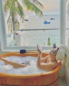 a woman in a bath tub with a view of the ocean at sunset beach house 3 in Phu Quoc