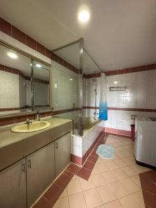 uma casa de banho com um lavatório, um chuveiro e um WC. em Riverbank Suite @ Waterfront KCH em Kuching