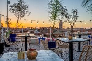 BÔ Riad Boutique Hotel & Spa في مراكش: فناء به طاولات وكراسي مع غروب الشمس في الخلفية