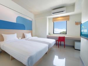 a hotel room with two beds and a red chair at Hop Inn Suphanburi in Suphan Buri