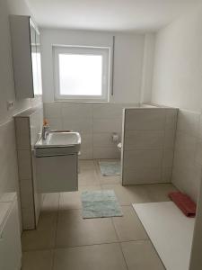 a white bathroom with a sink and a window at Ferienwohnung Landhege in Michelfeld