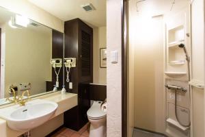 a bathroom with a sink and a toilet and a mirror at Kussharoko Sauna Club in Teshikaga