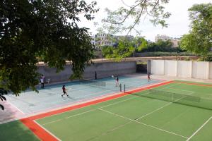 a group of people playing tennis on a tennis court at The Byke Grassfield Resort with Outdoor Pool, Shyam Nagar, Jaipur in Jaipur