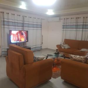 MAYRAH Inn - Your comfortable home from home in Freetown Sierra Leone في Goderich: غرفة معيشة مع كنبتين وتلفزيون بشاشة مسطحة