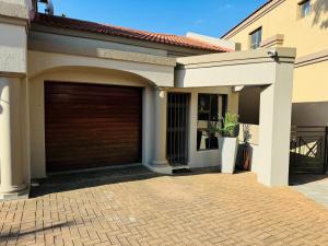 a house with a garage door on a brick driveway at Wisteria Place@3 Boschdal Rustenburg in Rustenburg