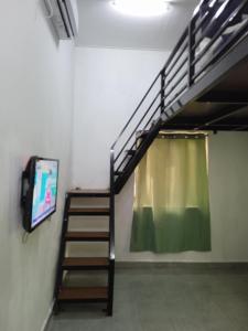 a staircase in a room with a curtain and a television at Tiny House Idaman Kuala Terengganu with Private House in Kuala Terengganu