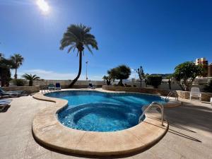 a swimming pool with a palm tree in the background at Apartamento en Porto Azul 12 in Calpe