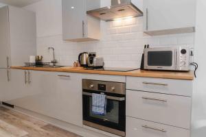 a kitchen with white cabinets and a microwave at Stunning Luxury Stay by VICHY in Hull