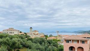 a town with a clock tower on a hill with trees at Appartement Les Oliviers L'ILE ROUSSE in LʼÎle-Rousse
