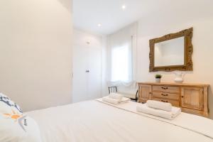 a white bedroom with a large bed and a mirror at Romantic: Precioso frente al mar in Sitges