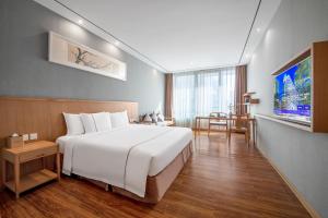 a bedroom with a large white bed and a table at H' Elite Hotel- Free Canton Fair Shuttle Bus and Registration Counter in Guangzhou