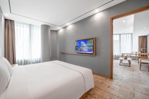 a bedroom with a white bed and a living room at H' Elite Hotel- Free Canton Fair Shuttle Bus and Registration Counter in Guangzhou