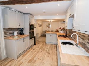 uma cozinha com armários brancos e piso em madeira em The Fox em Bridgnorth