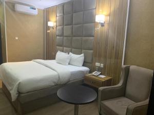 um quarto de hotel com uma cama e uma cadeira em VIEWPOINT HOTEL AND SUITES em Benin City
