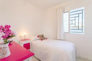 ein weißes Schlafzimmer mit einem Bett und einer Vase aus Blumen in der Unterkunft Bahamas III -Sant Joan- in San Juan de Alicante + 20 Fotos