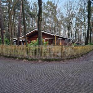 ein Holzhaus hinter einem Zaun neben einem Baum in der Unterkunft Vakantiechalet voor 4 plus 2 met sauna in Lanaken