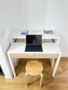 una scrivania bianca con computer portatile e sedia in legno di Modern Apartment Lungolago di Como a Como