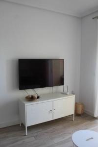 Elle comprend une armoire blanche dotée d'une télévision murale à écran plat. dans l'établissement Apartamento en Los Arenales, à Alicante