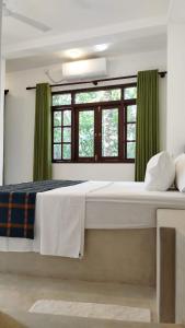una camera da letto con un grande letto con tende verdi di Sinali Villa a Habaraduwa Central