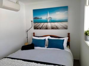 ein Schlafzimmer mit einem Bett mit einem Bild eines Segelboots in der Unterkunft Beachfront Tiny Townhouse Kurnell in Kurnell