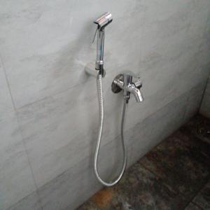 a shower with a hose attached to a wall at Mendonca's Home Stay in Pernem