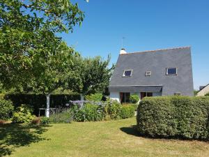 une maison avec une haie devant elle dans l'établissement Langlazic - Maison 3 chambres avec jardin, à Clohars-Carnoët