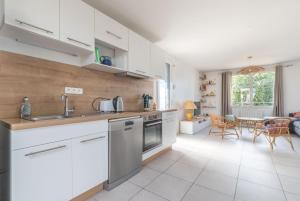 une cuisine avec des placards blancs et une salle à manger dans l'établissement L'Escampette - A 650m de la plage, à Saint-Nazaire