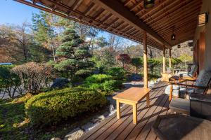 静かなお宿加賀美 في Shimojo mura: شرفة خشبية مع طاولة وحديقة