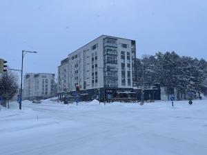 a snow covered street with a large building at Uusi kaksio Kaarinan keskustassa in Kaarina