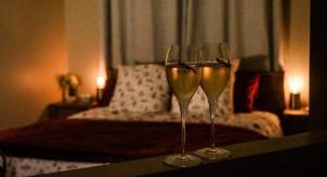 zwei Gläser Wein auf einem Tisch mit einem Bett in der Unterkunft La suite des charmelines in Fours-en-Vexin